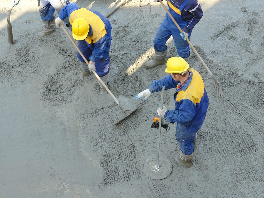 Construction workers spreading freshly poured concrete mix at the building site